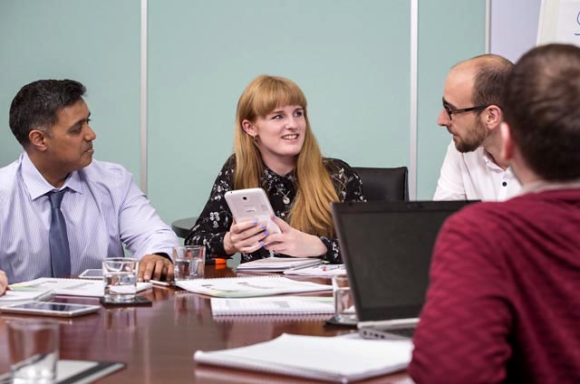 four people sat round a table in a business environment.